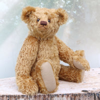 Brown teddy bear sitting on a wooden surface with a light background
