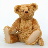 Cuthbert, a one of a kind antique gold teddy bear sitting on a white background