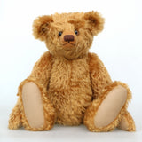Cuthbert, a one of a kind antique gold teddy bear sitting on a white background