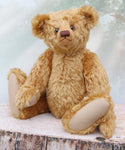 Brown teddy bear sitting on a wooden surface with a light background