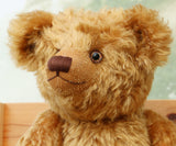 Close-up of a Cuthbert, a one of a kind antique gold teddy bear with a blurred background
