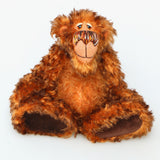 Denzel, a happy brown tipped ginger mohair artist bear by Barbara A Bears, photographed sitting against a plain light grey background.