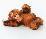 Denzel, a happy brown tipped ginger mohair artist bear by Barbara A Bears, photographed lying on his side against a plain white background.