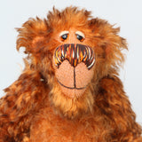 A close-up of Denzel's face, a happy brown tipped ginger mohair artist bear by Barbara A Bears, photographed to show his beautiful nose, amber eyes and beaming smile, against a plain light grey background.