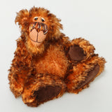 Denzel, a happy brown tipped ginger mohair artist bear by Barbara A Bears, photographed sitting against a plain light grey background.