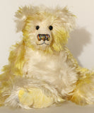 Dorothy teddy bear, a yellow and white hand dyed mohair teddy bear with a multicoloured nose against a white background