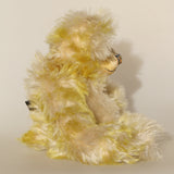 Dorothy teddy bear in profile, a yellow and white hand dyed mohair teddy bear with a multicoloured nose against a white background