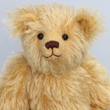 Close-up of Euan, a mohair collector's teddy bear with a soft texture on a light grey background