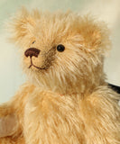 Close-up of Euan, a mohair collector's teddy bear with a soft texture on a light background