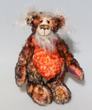 Flambé by Barbara Ann Bears,a distressed mohair teddy bear with mottled brown and black fur, a bright orange textured chest, and a white fuzzy beard