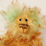 Green Eared Banana Stalker is a little, endearingly sweet and joyful, one of a kind, artist bear by Barbara-Ann Bears in wonderfully fluffy mohair, he stands 6.5 inches/17 cm tall. He is mostly made from a long golden mohair with brown tipping, with hand dyed green mohair ears, and beige wool felt paw pads. He has hand painted glass eyes with hand coloured eyelids, a wonderfully embroidered nose and a broad and cheerful smile. 