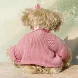 back view of Little Rowena a vintage Barbara Ann teddy bear in a pink knitted cardigan with her name tag on a wooden surface