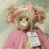Close up of Little Rowena, a vintage Barbara Ann teddy bear in a pink knitted cardigan and pink ribbon
