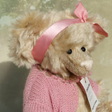 Close up of Little Rowena, a vintage Barbara Ann teddy bear in a pink knitted cardigan and pink ribbon