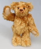 Owen, a traditional antique gold teddy bear standing and waving on a light grey background