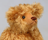 close-up of Owen, a traditional antique gold teddy bear on a light grey background