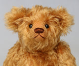 close up of Owen, a traditional antique gold teddy bear on a light grey background