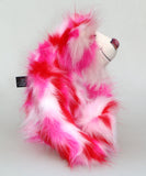 Pamela Pinkerton a colourful teddy bear with pink and white fur and a multicoloured mouth on a white background sitting in profile