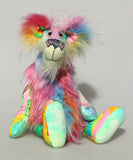 Plinkety Plonk by Barbara Ann Bears sitting down. He's a wildly colourful bear in printed fabric, long fluffy mohair and very long multi coloured faux fur.