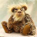 Tarzan McKenzie sitting. He is a very fashionable and exotic, one of a kind, artist bear by Barbara-Ann Bears in leopard print faux fur and fluffy gold mohair. He has ochre felt paw pads, hand painted glass eyes, a beautifully embroidered nose and a huge smile.