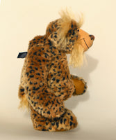 Tarzan McKenzie standing, side profile. He is a very fashionable and exotic, one of a kind, artist bear by Barbara-Ann Bears in leopard print faux fur and fluffy gold mohair. He has ochre felt paw pads, hand painted glass eyes, a beautifully embroidered nose and a huge smile.