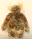 Tarzan McKenzie standing, back view. He is a very fashionable and exotic, one of a kind, artist bear by Barbara-Ann Bears in leopard print faux fur and fluffy gold mohair. He has ochre felt paw pads, hand painted glass eyes, a beautifully embroidered nose and a huge smile.