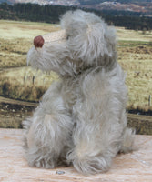 Wolfie sitting in profile.
Wolfie is a wild and groovy guy, a veteran artist bear from Barbara-Ann Bears in silvery grey English mohair, he stands 10 inches/25 cm tall. 