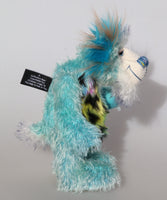 Billy Calypso is made from a sparse mohair hand dyed sky blue, his tummy is a long blue, yellow and magenta faux fur with black spots and his face and the underside of his tail are a long white mohair with blue tipping. On top of Billy's head and on the backs of his ears is a long aqua faux fur with tufts of warm beige. Billy has hand-dyed velvet paw pads. Billy has beautiful hand painted eyes with eyelids, a nose embroidered from individual threads and he has a huge, friendly smile