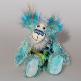 Billy Calypso is made from a sparse mohair hand dyed sky blue, his tummy is a long blue, yellow and magenta faux fur with black spots and his face and the underside of his tail are a long white mohair with blue tipping. On top of Billy's head and on the backs of his ears is a long aqua faux fur with tufts of warm beige. Billy has hand-dyed velvet paw pads.  Billy has beautiful hand painted eyes with eyelids, a nose embroidered from individual threads and he has a huge, friendly smile