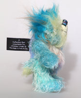 Bim-Bam is made from several different mohairs, he's mainly a medium length, slightly distressed and sparse mohair hand dyed a beautiful aqua, his tummy is a slightly longer, dense mohair hand dyed in silver, with hints of blue and purple, his back is shorter, sparse mohair dyed sky blue and his face, the fronts of his ears and the underside of his tail are a longer, fluffy mohair hand-dyed a light, happy yellow. The top of his head is a plume of aqua faux fur. Bim-Bam has hand dyed velvet paw pads