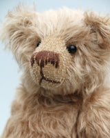 Buster is a very sweet and friendly, quite traditional, one of a kind, mohair artist teddy bear by Barbara Ann Bears, he stands 10 inches/25 cm tall and is 7.5 inches/19 cm sitting. Buster is made from beautiful, quite sparse, fairly straight, soft beige mohair, with German wool-felt paw pads and spherical, glass eyes