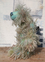 Byron is a wild thing, yet a very friendly wild thing, a one of a kind, hand dyed mohair artist bear by Barbara-Ann Bears, he stands 10.5 inches (26 cm) tall and is 8 inches (20 cm) sitting. He is made from a gorgeous, long, straggly mohair that Barbara has dyed in jade, turquoise with some green, amber and sky blue