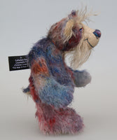 Clarence Sunbeam is a loveable and subtly coloured, one of a kind artist bear, in muted hand dyed mohair by Barbara-Ann Bears, he stands 8 inches/20 cm tall. Clarence Sunbeam is mostly made from a fairly short and sparse mohair hand dyed in indigo, lilac, mauve, rose and ultramarine with splashes of rusty amber.  His face is a very long, feathery pale beige mohair and the backs of his ears and the underside of his tail are a similarly coloured shorter, twirly mohair