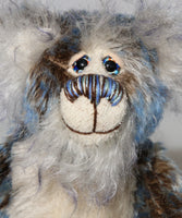 Danny Dalrymple has beautiful, hand painted eyes with eyelids, a splendid nose embroidered from individual threads to complement his colouring and he has a sweet, friendly smile. His main mohair is a slightly wavy German mohair that has a dark brown base, the tips were then bleached and then the very ends dyed blue and his face, the fronts of his ears and the underside of his tail are a long fluffy white mohair tipped with blue