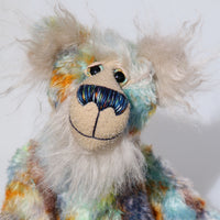 Elgar is made from a beautiful medium length mohair hand dyed in sky blue, emerald, lime, gold, amber and a greyish brown. His face, tummy, the underside of his tail and the fronts of his ears are a very long and luxuriously fluffy, pearly white mohair with a warm alabaster coloured backcloth. The velvet for Elgar's has paw pads was dyed with his mohair. Elgar has beautiful, hand painted eyes with hand coloured eyelids, a nose embroidered from individual threads to match his colouring and a gentle smile