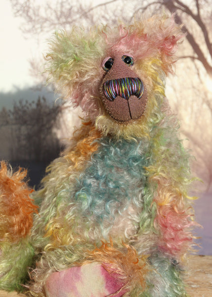 Emerson Ploom an elegant colourful, one of a kind, hand dyed mohair artist bear by Barbara-Ann Bears. He stands 16.5 inches (42 cm) tall and is 13 inches (33 cm) sitting and is made from long distressed mohair hand dyed in greens, blues, ambers, pinks, oranges, golds and lilac, the backcloth has been dyed a dull mauve