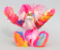 Fandango is mostly made from a gorgeous multicoloured faux fur, it has patches of magenta, orange, yellow, blue and violet and his tummy and the top of his tail are a much longer faux fur in coordinating shades of pink and white. His face and the fronts of his ears are a long white mohair and on top of his head head he has a plume of long and fluffy magenta faux fur. Fandango's paw pads are each a different colour of hand dyed cotton velvet picked from his colouring; pink, yellow, orange and blue. 