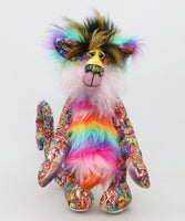 Faustus is mostly made from a very bright and colourful, monstrous cotton fabric. The sides of Faustus' face are a very long pale pink mohair with a dusky lavender-pink backcloth and the top of his nose is a long, fluffy mohair hand dyed yellow. His tummy and the backs of his ears are a long faux fur in bands like a rainbow and on top of his head he has a long black faux fur with plumes of yellow, magenta and teal. Faustus' footpads are made from hand dyed velvet.
