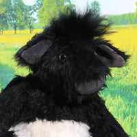 Gertie is mostly made from a fairly long and distressed black faux fur which is remarkably cow-like. Her tummy band is a fairly long and distressed white mohair and the fronts of her ears, nose and hoofs are a dark grey velvet. The top of her head and the tip of her tail are a much longer black faux fur.  Gertie has large clear glass eyes and is mostly stuffed with polyester stuffing, she has plastic pellets in her tummy and glass beads in her hoofs to make them a little heavier.