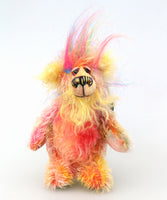 Jemermy is mainly made from a fairly short, quite sparse mohair hand dyed in many natural shades, pink and gold with splashes of purple and blue, his tummy and the underside of his tail are a longer mohair dyed in pinks and soft yellow, his face is a long mohair dyed a bright, happy yellow and the fronts of his ears are a denser, curlier mohair dyed a bright yellow. On top of his head there is a plume of long faux fur in blue, pink and yellow. Jeremy has hand dyed velvet paw pads. 