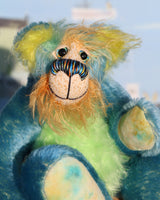 Larry Lagoon is a calm and happy, one of a kind mohair artist bear by Barbara-Ann Bears, he stands 10 inches/25 cm tall and is 7.5 inches/19 sitting. Larry Lagoon captures the colours of a tropical island with his his blue like a calm Caribbean sea mixed with flashes of colour like birds or exotic flowers. 