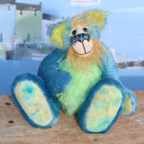 Larry Lagoon is a calm and happy, one of a kind mohair artist bear by Barbara-Ann Bears, he stands 10 inches/25 cm tall and is 7.5 inches/19 sitting. Larry Lagoon captures the colours of a tropical island with his his blue like a calm Caribbean sea mixed with flashes of colour like birds or exotic flowers. 