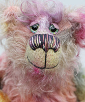 Lonnie Puckleton's beautiful eyes were hand painted to match his mohair as were his hand coloured eyelids. His nose was embroidered with individual threads to match his colouring and he has a beaming smile. Lonnie is made from a sparse mohair hand dyed in emerald, rose, grey, peach, purple, blonde and lilac. His tummy is a dense wavy mohair in dusky rose and his face, ears and the underside of his tail are made from a long, scraggly mohair in pale lilac, pistachio and mauve