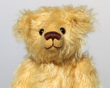 Marigold's Teddy is made from gorgeous slightly distressed golden blond German mohair, he has old, black boot buttons for eyes and beige wool felt paw pads. He has a pert, little, carefully embroidered brown nose and the sweetest smile