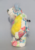 Pascual is made from printed fabric, the base colour is almost white, on top of this there are many flowers in blues, pinks, yellows and greens. His tummy is a long and fluffy faux fur in pink and yellow, his face is a very long and fluffy white mohair and the fronts of his ears and the underside of his tail are a very long and fluffy powder blue mohair. Pascual has beautiful hand painted glass eyes with eyelids, a wonderfully embroidered nose and a beaming smile