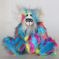 Pedro Piccolo is mostly made from a fairly long and fluffy multi-coloured faux fur in sky blue with flashes of yellow, magenta, orange and mauve. His face, the fronts of his ears and the underside of his tail are a very long and fluffy white mohair. Pedro Piccolo has blue velvet paw pads which complement his colouring perfectly. He has beautiful, hand painted glass eyes with eyelids, a wonderful nose embroidered from individual threads to match his colouring and a charming smile