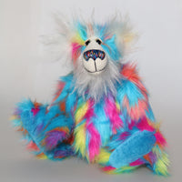 Pedro Piccolo is mostly made from a fairly long and fluffy multi-coloured faux fur in sky blue with flashes of yellow, magenta, orange and mauve. His face, the fronts of his ears and the underside of his tail are a very long and fluffy white mohair. Pedro Piccolo has blue velvet paw pads which complement his colouring perfectly. He has beautiful, hand painted glass eyes with eyelids, a wonderful nose embroidered from individual threads to match his colouring and a charming smile