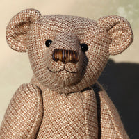 Tweedy is a an elegant and refined traditional Barbara Ann Bear made in a very dapper tweed from tweed maker Romney Tweed, he is 16 inches (38cm) tall and is 11 inches (30cm) sitting. Tweedy is made from tweed with a golden brown and creamy beige pattern his paw pads are tweed, in a brown, beige and blue tartan