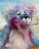 Tim Pimpling is a happy, little one of a kind, mohair artist bear by Barbara-Ann Bears. Tim stands 6.5 inches( 16 cm) tall and is 5 inches ( 13 cm) sitting. He is mostly made from a medium length, slightly distressed and fluffy mohair that Barbara has hand dyed in sky blue with some splashes of magenta, pink and lilac