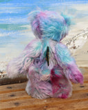 Tim Pimpling is a happy, little one of a kind, mohair artist bear by Barbara-Ann Bears. Tim stands 6.5 inches( 16 cm) tall and is 5 inches ( 13 cm) sitting. He is mostly made from a medium length, slightly distressed and fluffy mohair that Barbara has hand dyed in sky blue with some splashes of magenta, pink and lilac